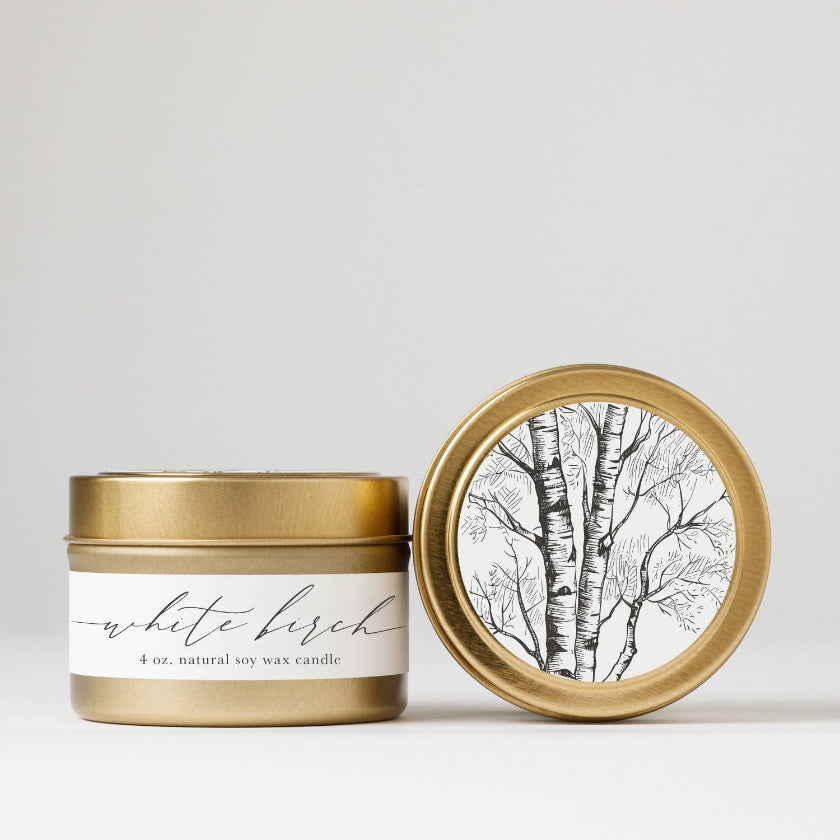 Gold candle jar with 'white birch' label and matching lid on a light background