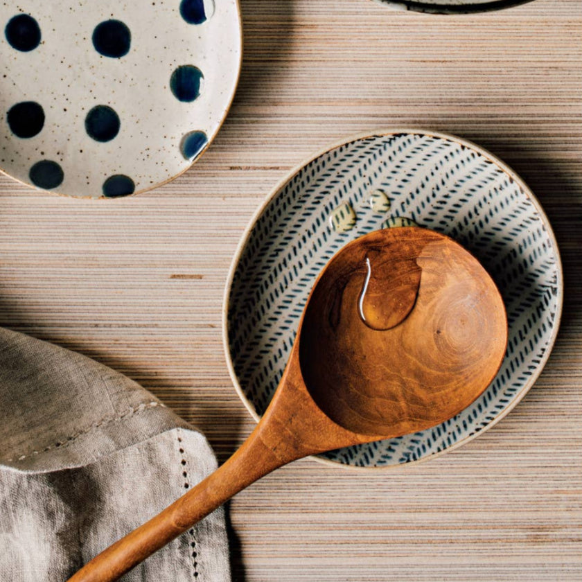 Decorative ceramic plates with polka dots and textured patterns on a wooden surface, with a wooden spoon and walnuts.