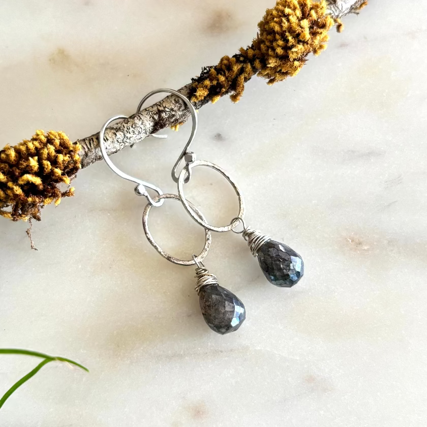 Silver earrings with teardrop-shaped stones on a natural background