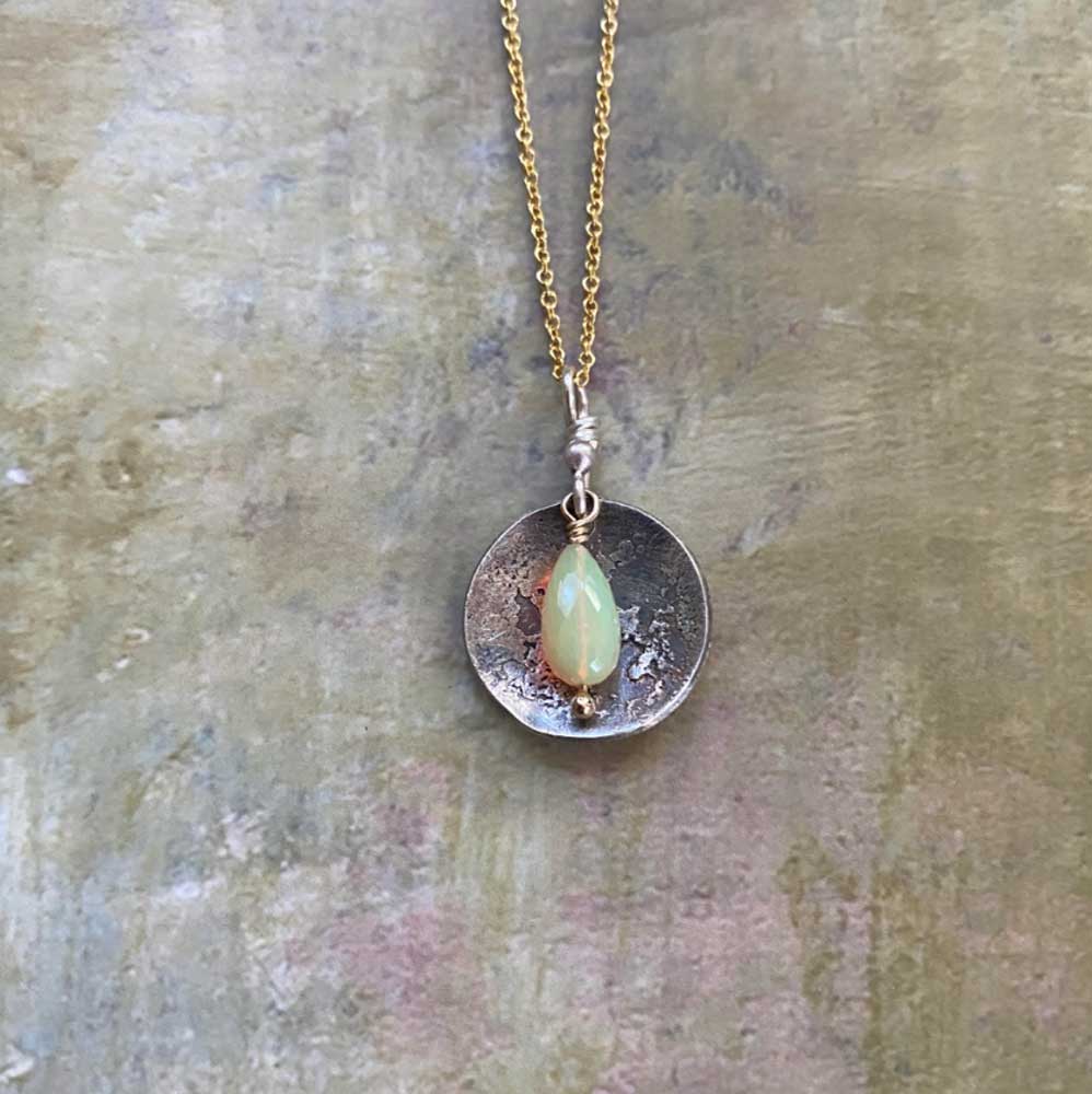 Necklace with a pendant featuring a green stone on a textured surface
