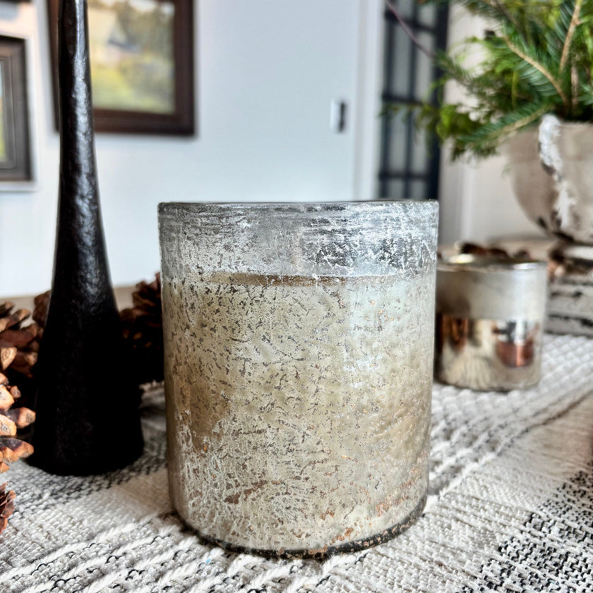 Textured glass candle holder on a decorative surface with a blurred indoor background