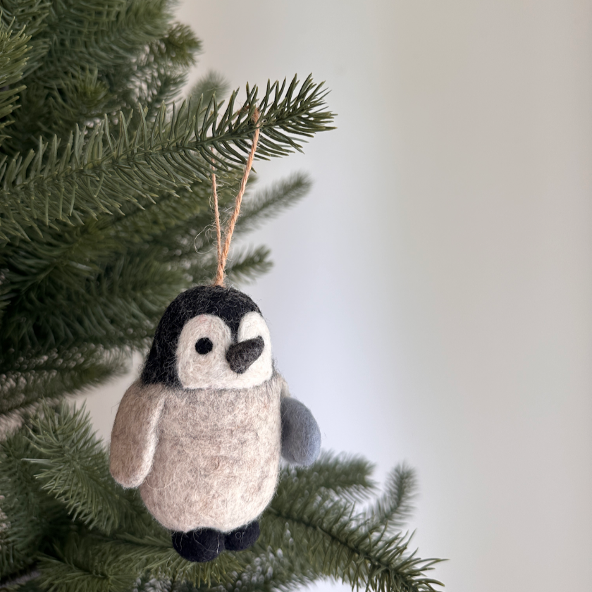 Felt penguin ornament hanging on a Christmas tree branch
