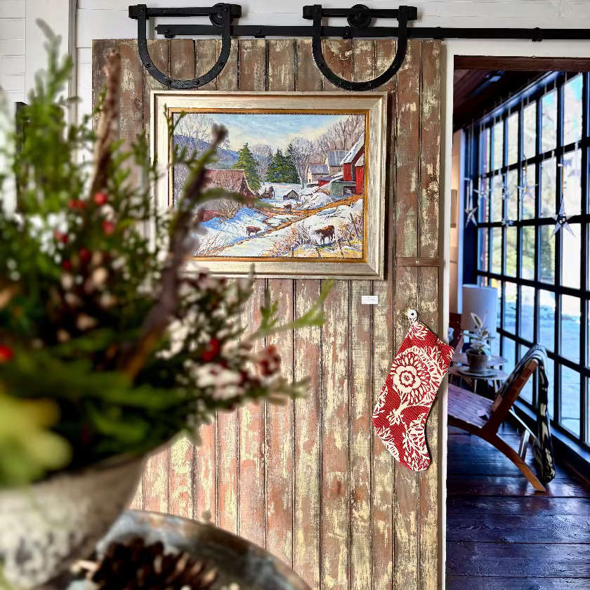 Decorative interior with a painting on a wooden panel, plants, and a red patterned item.