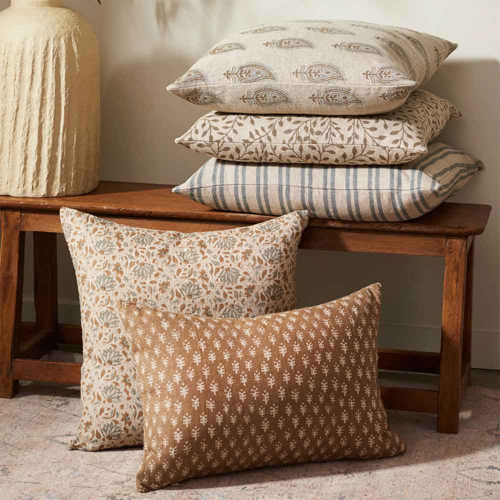 Patterned pillows on a wooden bench against a neutral wall.