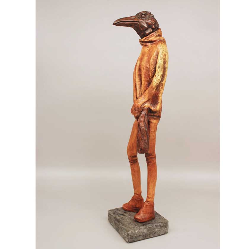 Statue of a figure with a long nose, wearing a coat and boots, on a gray background