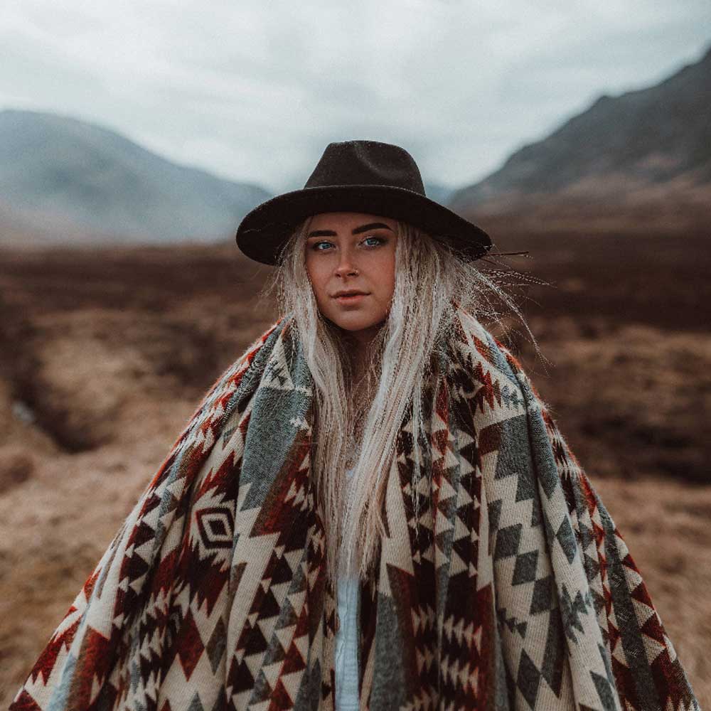 Person wrapped in a patterned blanket with mountains in the background