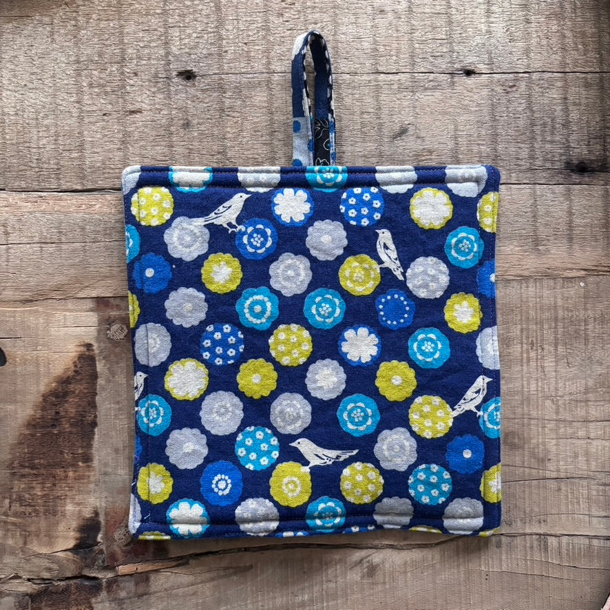 Pair of blue pot holders with floral pattern on a wooden surface