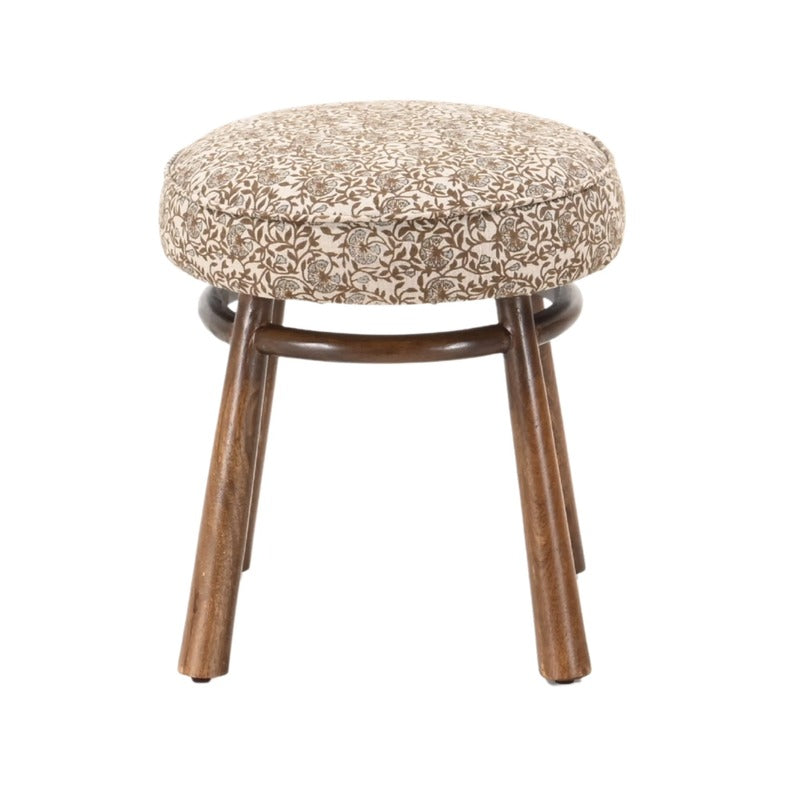 Round floral block print linen ottoman with warm wood legs and curved stretcher base.