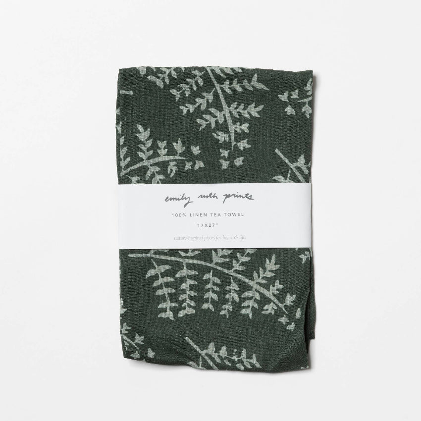 Green linen tea towel with white leaf pattern on a white background
