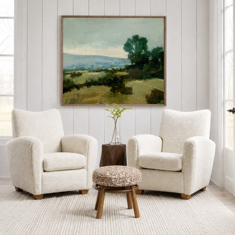 Round floral block print linen ottoman with warm wood legs and curved stretcher base.
