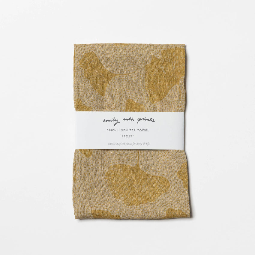 Linen tea towel with floral pattern and brand label on a white background