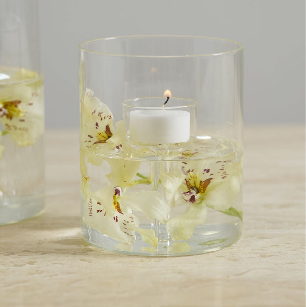 Clear glass with a floating candle and flowers on a wooden surface