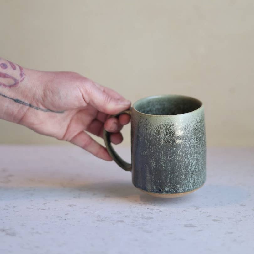 Gravesco Pottery moss green handmade stoneware mug held in hand, gray background
