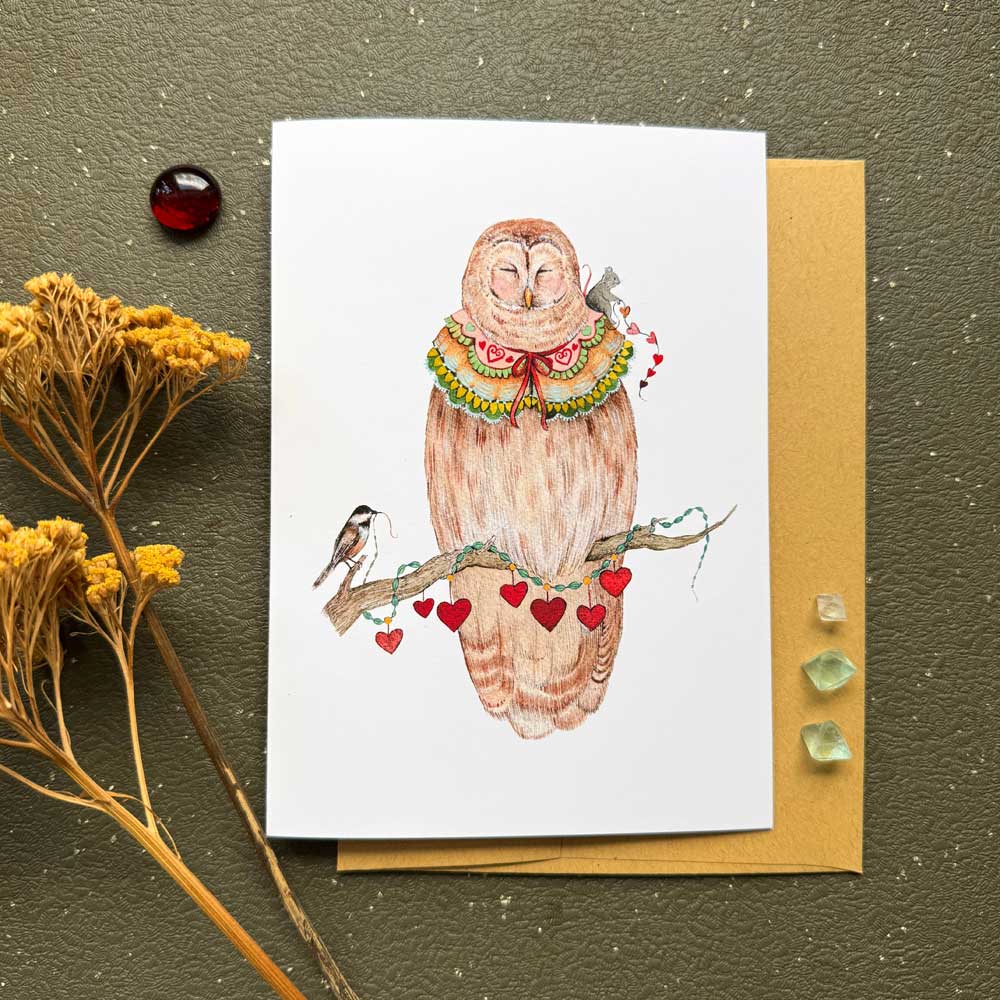 Greeting card with an owl illustration on a textured surface with decorative elements.