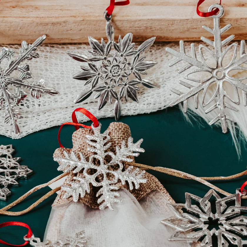 Decorative snowflake ornaments with red ribbons on a green surface