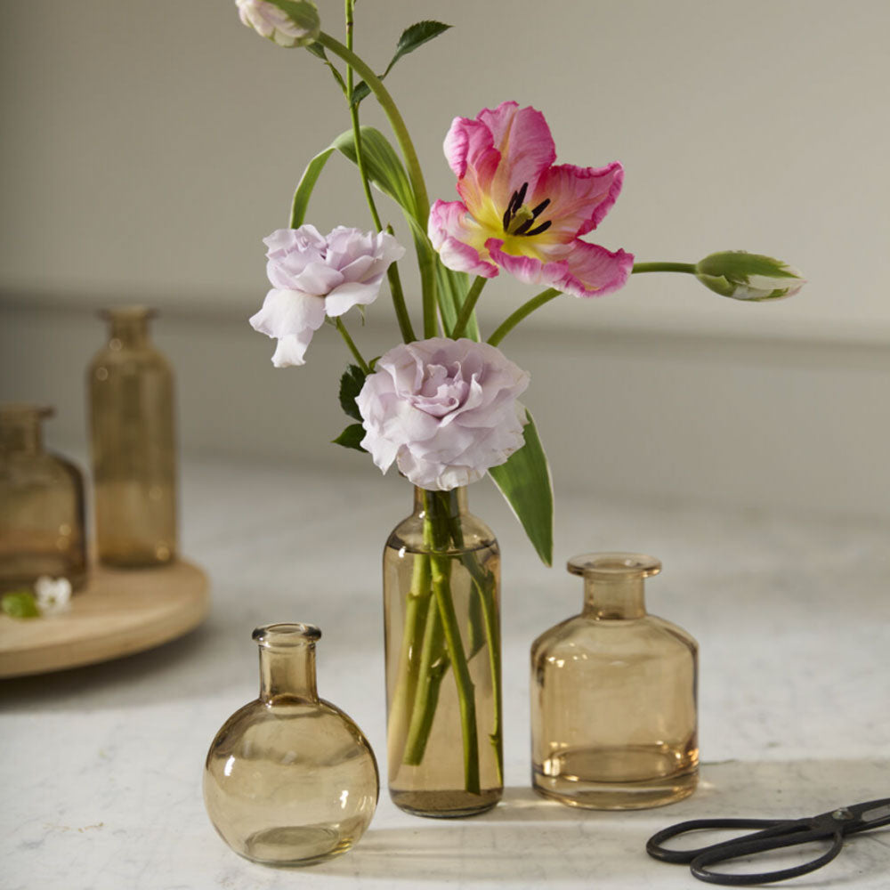 Vases and flowers on a marble surface with a neutral background