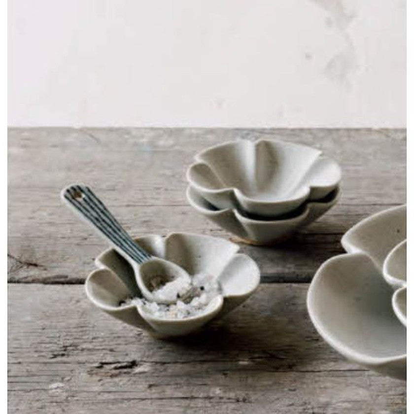 A set of beige stoneware pinch bowls with a floral pattern, displayed on a wooden surface.